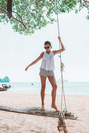 Young woman on swings on a sea beachの写真素材