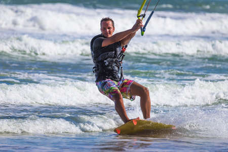 Athletic man riding on kite surf board on a sea wavesの写真素材