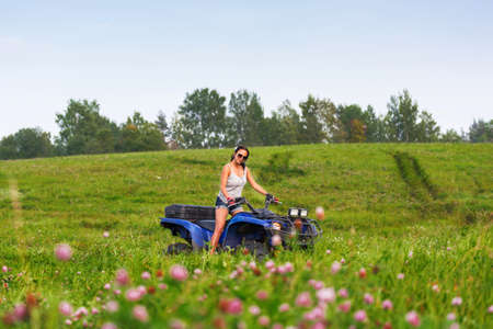 Elegant woman riding quadrocycle ATV on a green fieldの写真素材