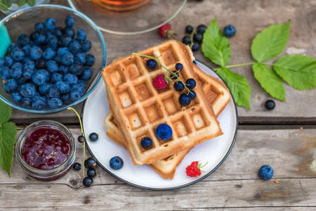 Fresh homemade waffles with blackberries, Jam, tea, leaves, berries on woodenの写真素材