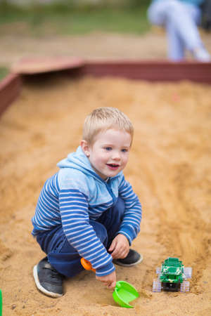 Little boy playing with a toy car in the sandbox on the children playgroundの写真素材