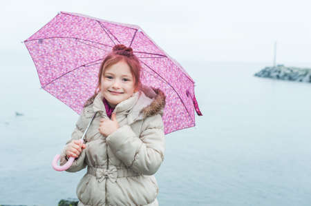 close up portrait of a little girl with pink umbrella under the rainの写真素材
