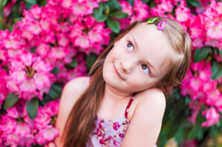 Cute little girl is daydreaming in pink flowersの写真素材