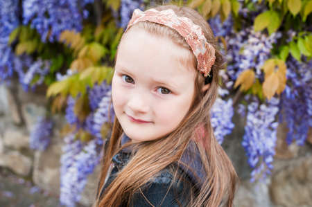 Spring portrait of a cute little girl, wisteria on backgroundの写真素材