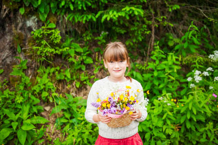 Portrait of a cute little girl with basket with flowersの写真素材