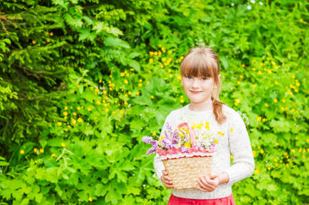 Portrait of a cute little girl with basket with flowersの写真素材