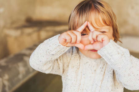 Outdoor portrait of a cute toddler boy pretending to take a picture with his handsの写真素材