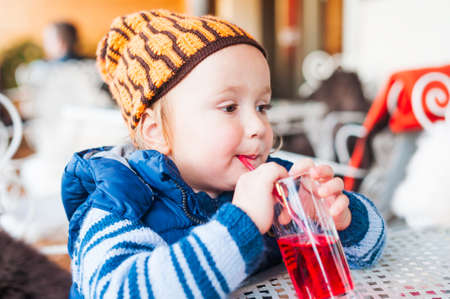 Cute toddler boy drinking syrup in a cafeの写真素材