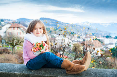Outdoor portrait of a beautiful little girl with bouquet of spring flowersの写真素材