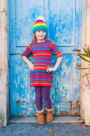 Beautiful little girl in a colorful dress and hat posing outdoorsの写真素材