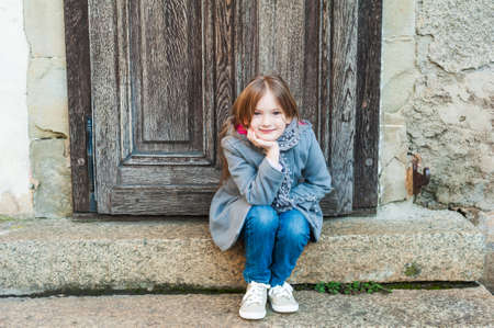 Outdoor portrait of a cute little girl in a grey coat