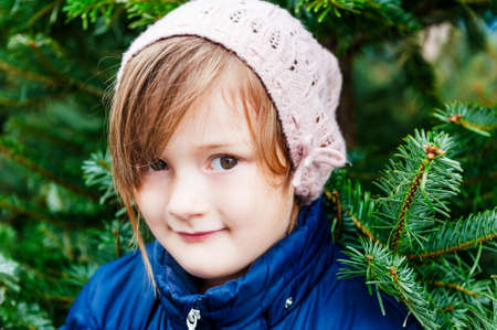 Close up portrait of a cute little girl in winter time with spruce on backgroundの写真素材