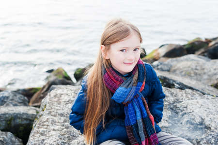 Outdoor portrait of a cute little girl next to lake on a nice dayの写真素材
