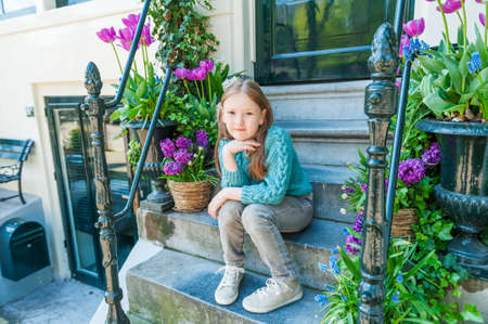 Outdoor portrait of a cute little girl sitting on steps in a city on a nice spring dayの写真素材