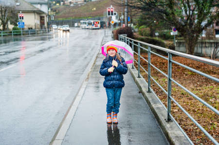 Cute little girl with umbrella in a city on a rainy dayの写真素材