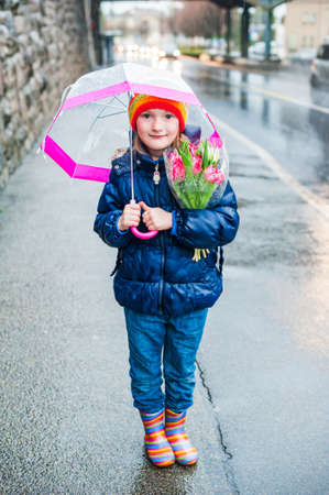 Outdoor portrait of a cute little girl in a city on a rainy dayの写真素材