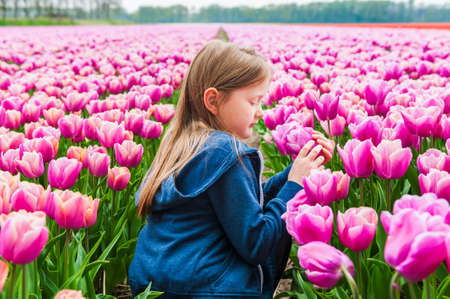 Cute little girl playing in a tulip fieldの写真素材