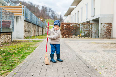 Cute little boy sweeping the backyard on a early spring dayの写真素材