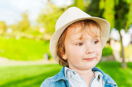 Outdoor portrait of adorable toddler boy on a nice sunny day, wearing a hatの写真素材