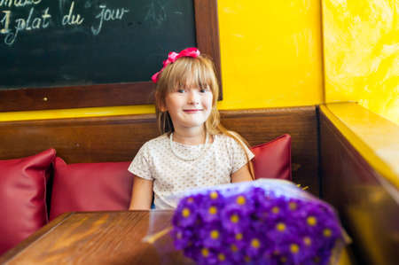 Portrait of a pretty little girl with pearl neckless in a cafe