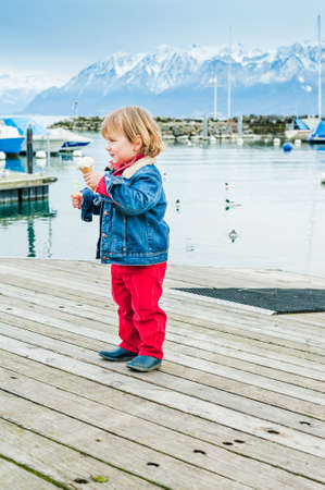 Adorable toddler boy eating ice cream in a portの写真素材