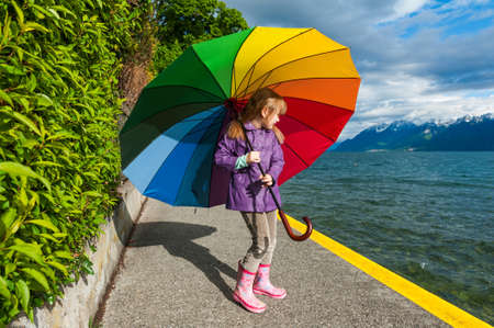 Outdoor portrait of a cute little girl, wearing rain jacket and bootsの写真素材