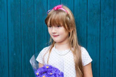 Adorable little girl with bouquet of violet flowers