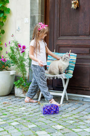 Adorable happy little girl and a cat outdoorsの写真素材