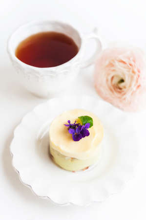 Small pistachio cake with fresh violet flowers on itの写真素材