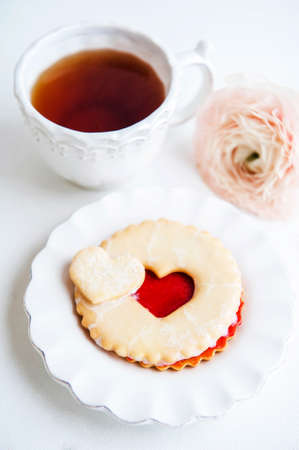 A cookie with strawberry jam and cup of teaの写真素材