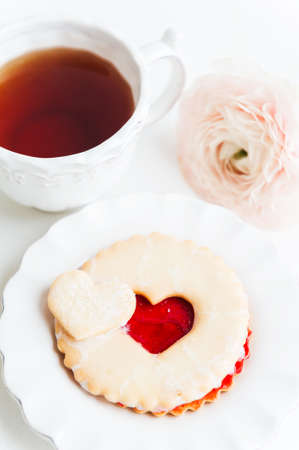 A cookie with strawberry jam and cup of teaの写真素材