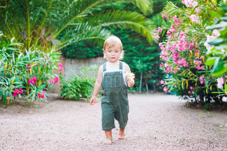 Adorable toddler boy walking with flowers in his handの写真素材