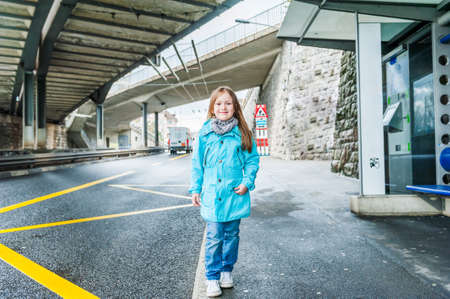 Outdoor portrait of a beautiful little girl in a blue jacketの写真素材