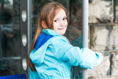 Outdoor portrait of a beautiful little girl in a blue jacketの写真素材