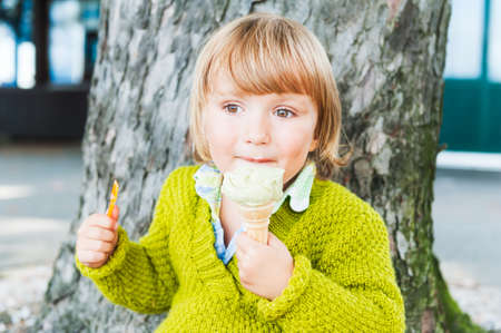 Portrait of a cute toddler boy eating pistachio ice cream outdoorsの写真素材
