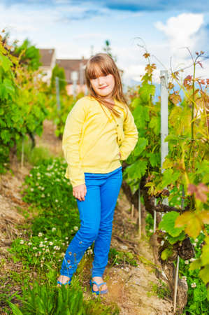Outdoor portrait of a cute little girl, wearing yellow top and blue pantsの写真素材
