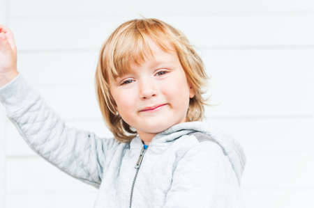 Outdoor portrait of a cute toddler boy in jeans, shirt and moccasins, standing against vineyardsの写真素材