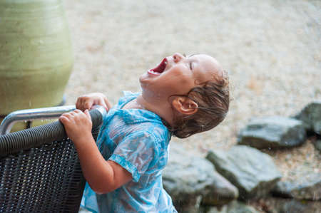 Cute baby boy playing under the rainの写真素材