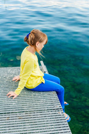 Outdoor portrait of a cute little girl, wearing yellow top and blue pantsの写真素材