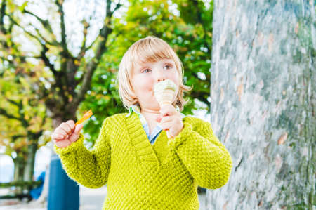 Portrait of a cute toddler boy eating pistachio ice cream outdoorsの写真素材