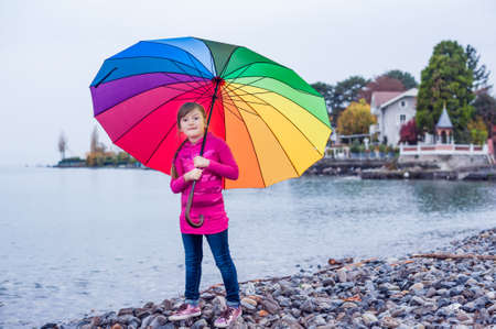 Portrait of a cute little girl with big colorful umbrellaの写真素材