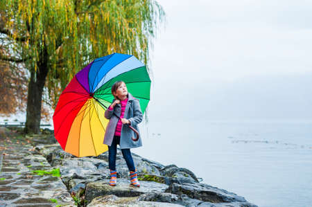 Portrait of a cute little girl with big colorful umbrellaの写真素材