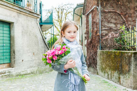 Cute little girl with beautiful bouquet of tiger roses, outdoorsの写真素材