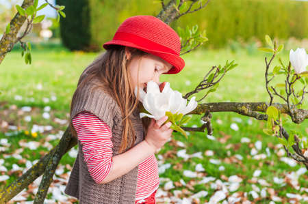 Spring portrait of a beautiful little girl in a red hatの写真素材
