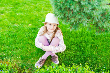 Outdoor portrait of adorable little girl sitting on grassの写真素材