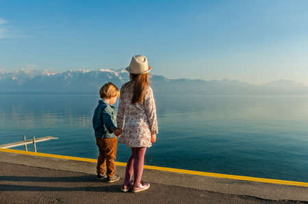 Adorable children resting next to lake on a nice sunny dayの写真素材