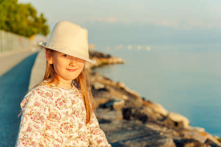 Sunset porait of a cute little girl, resting next to edge of the lakeの写真素材