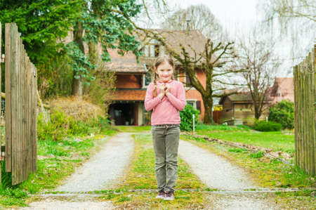 Adorable little girl standing against beautiful house on a nice spring dayの写真素材