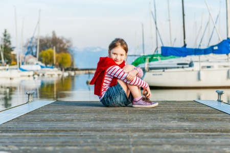 Cute little girl resting on a pier on a nice sunny dayの写真素材