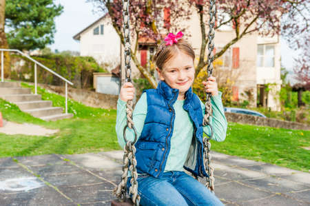 Spring portrait of a cute litle girl playing on playgroundの写真素材